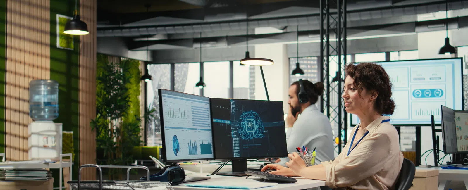 Woman working on AI and data analytics projects on computer screens in a modern office environment.
