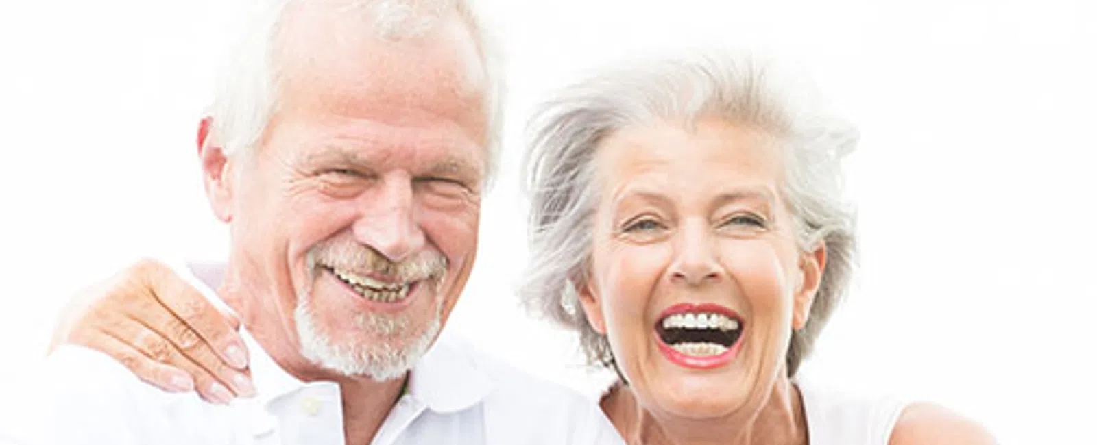Happy elderly couple smiling and embracing each other against a bright white background.