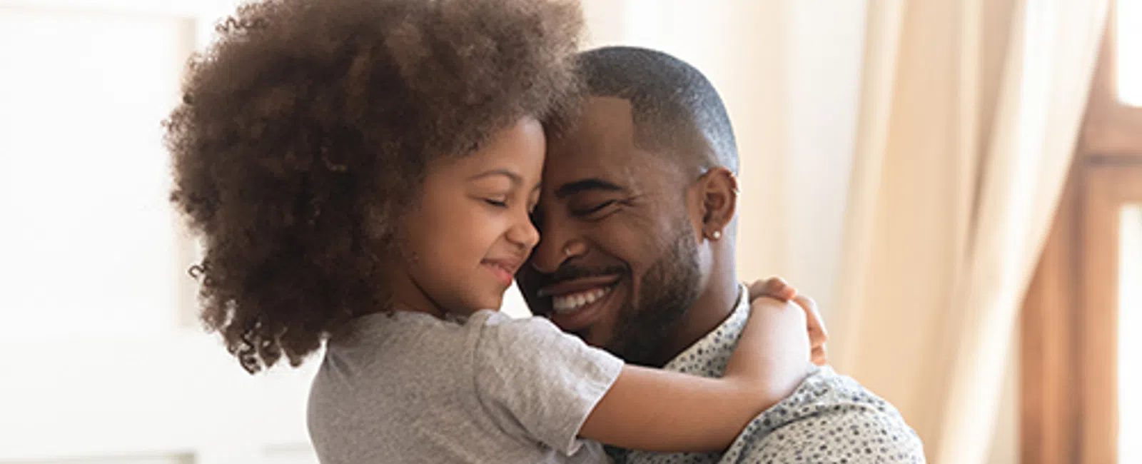 Father and daughter sharing a warm, loving embrace in a cozy, sunlit living room setting.