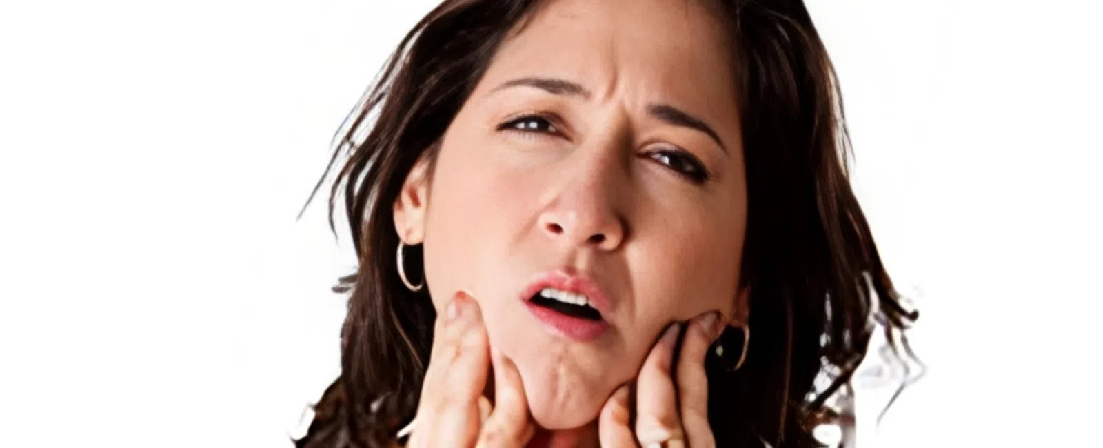 Woman in black tank top experiencing jaw pain holding her face with both hands against a white background