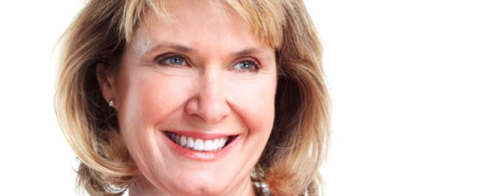 Smiling middle-aged woman with blonde hair wearing a coral top against a white background