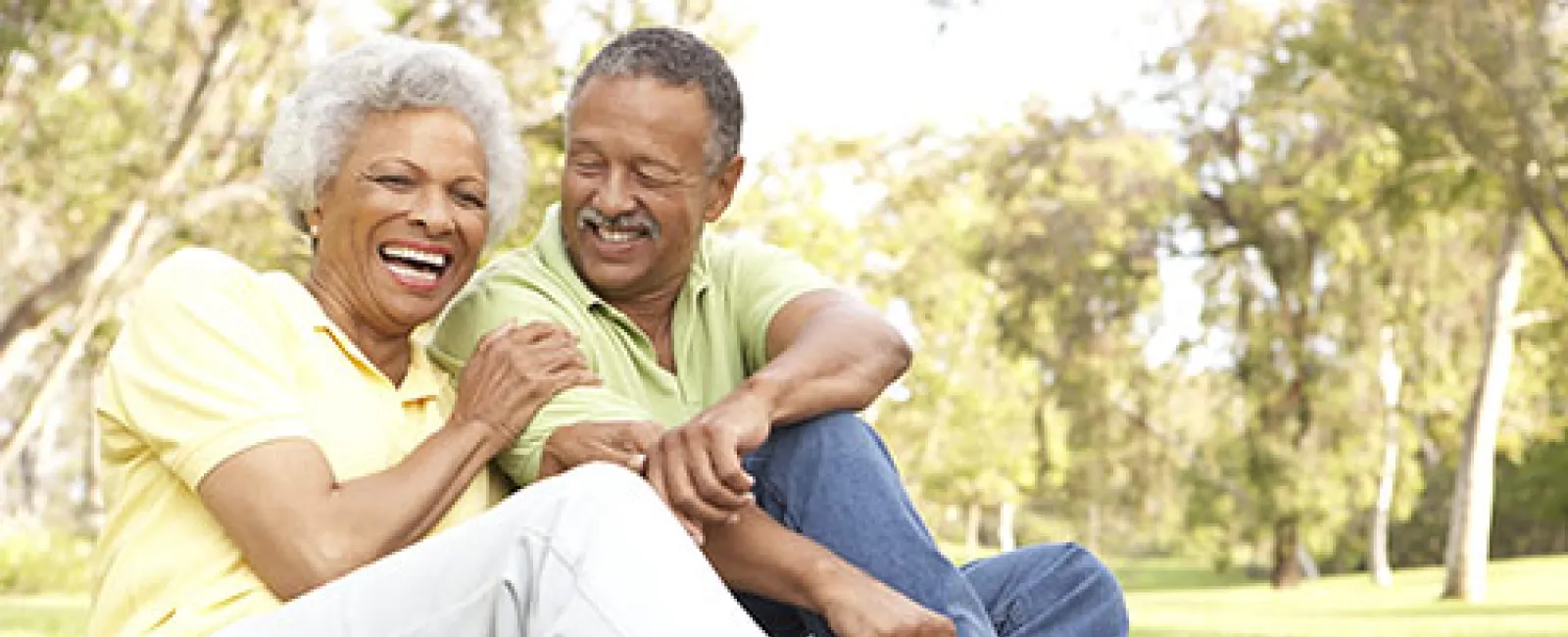 Happy older couple enjoying roller skating outdoors in a sunny park, smiling and sharing a joyful moment.