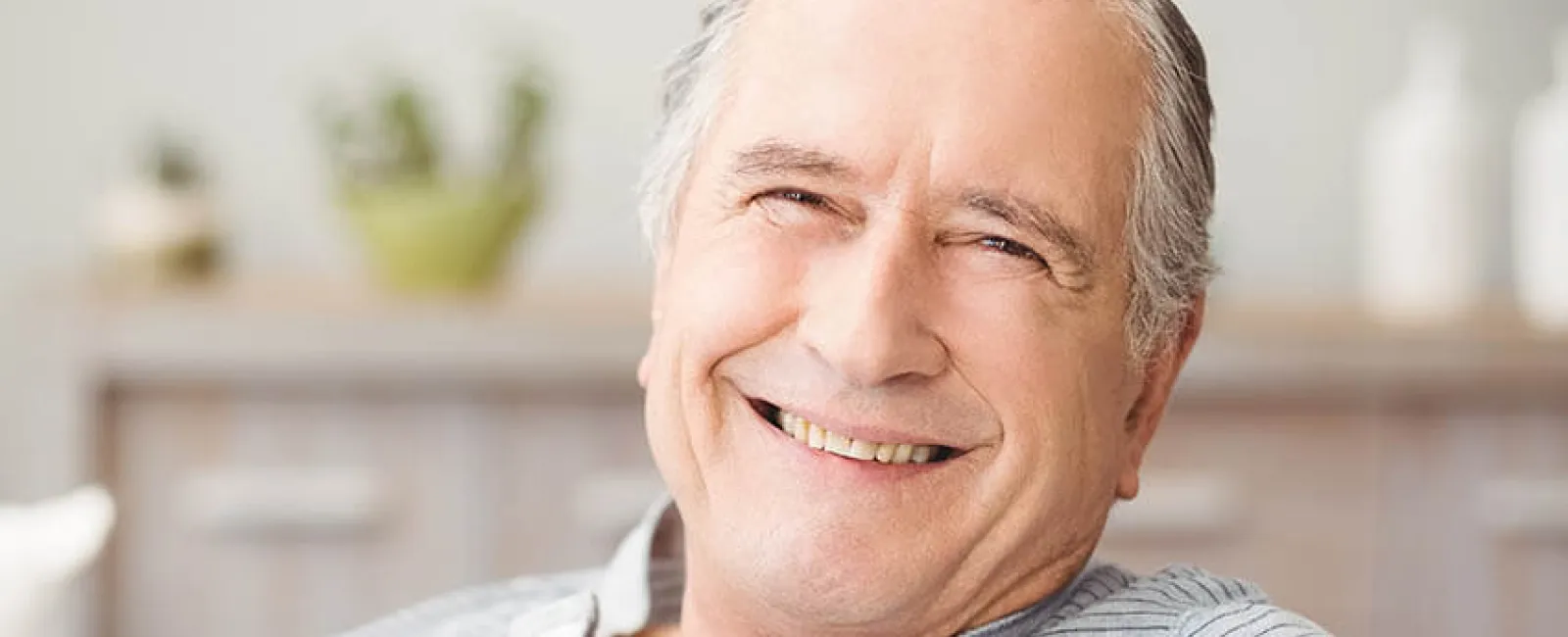 Smiling senior man relaxing at home, conveying warmth and happiness in a cozy environment.