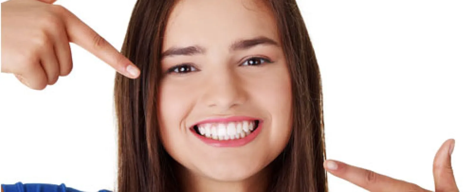 Smiling young woman pointing to her bright, white teeth with long brown hair.