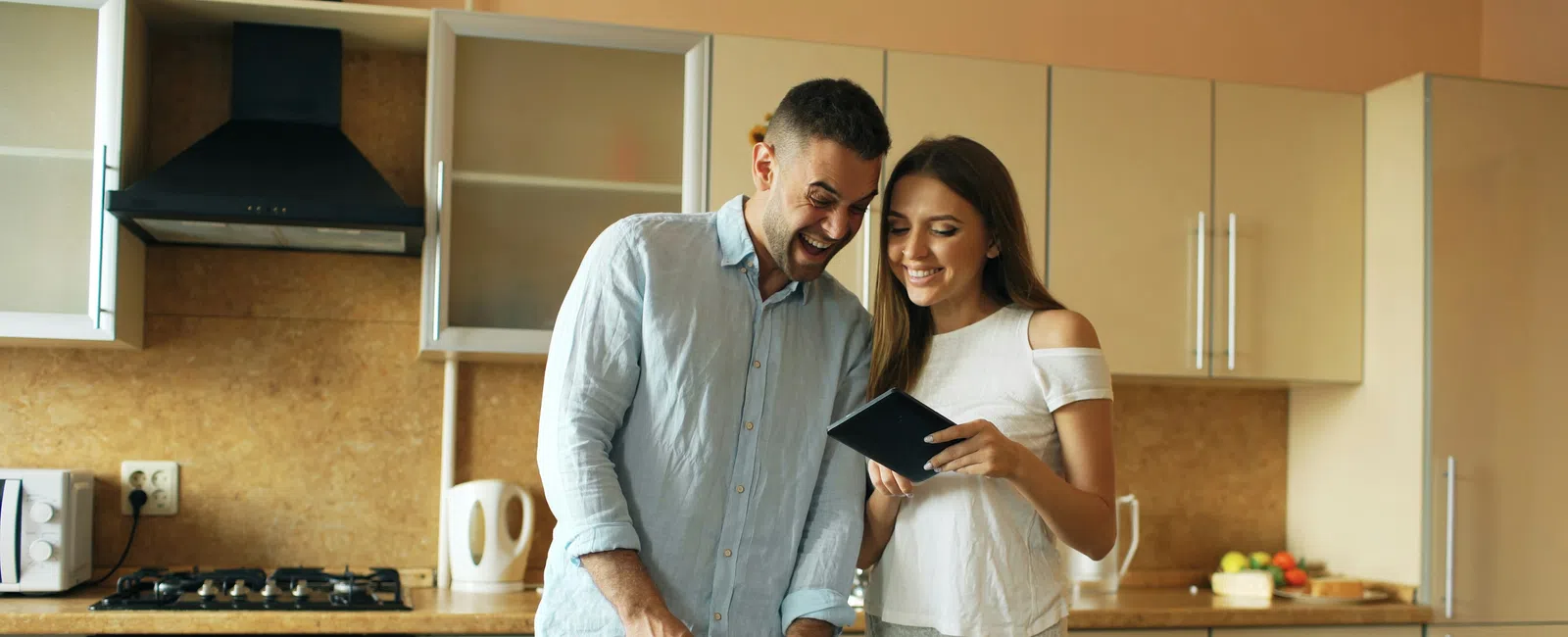 Couple cooking together in modern kitchen using tablet and slicing vegetables on cutting board