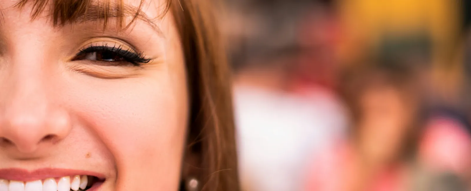Close-up of a smiling woman's face with brown hair and bright eyes in natural light
