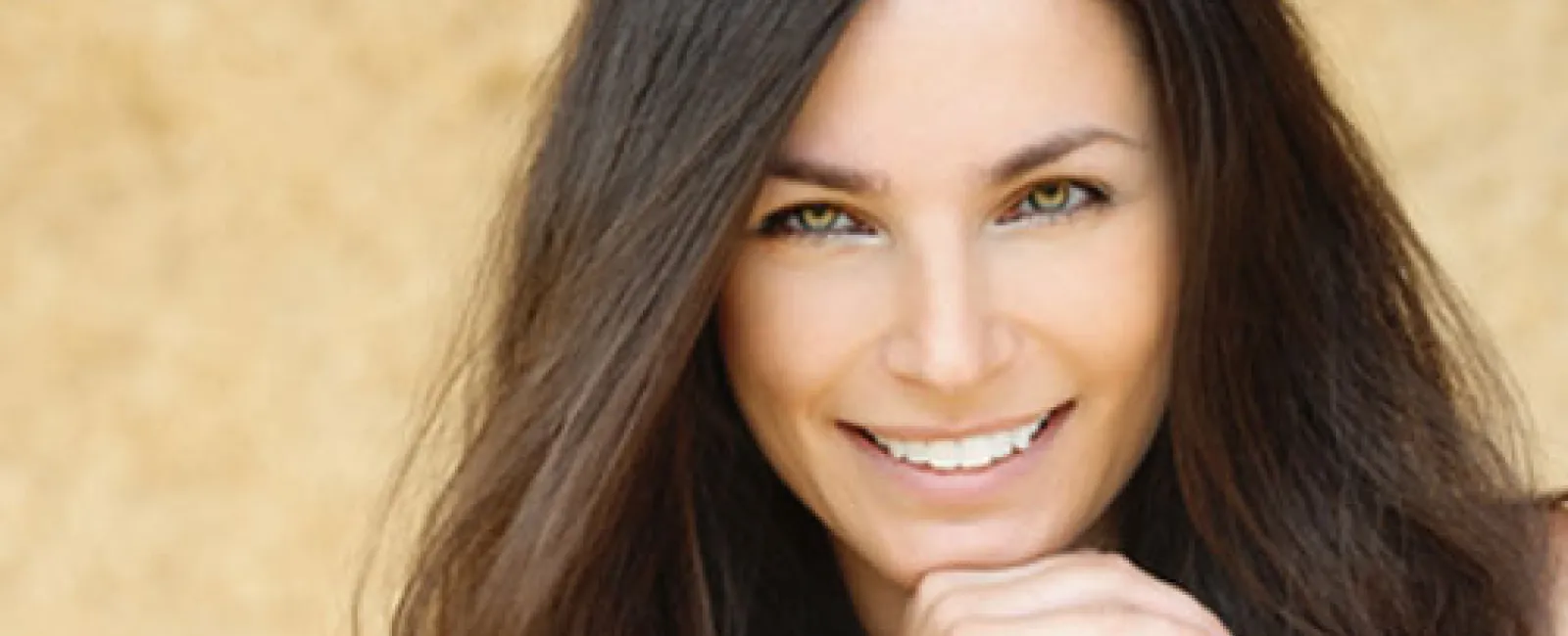 Smiling woman with long dark hair, showcasing a warm and inviting expression against a neutral background.