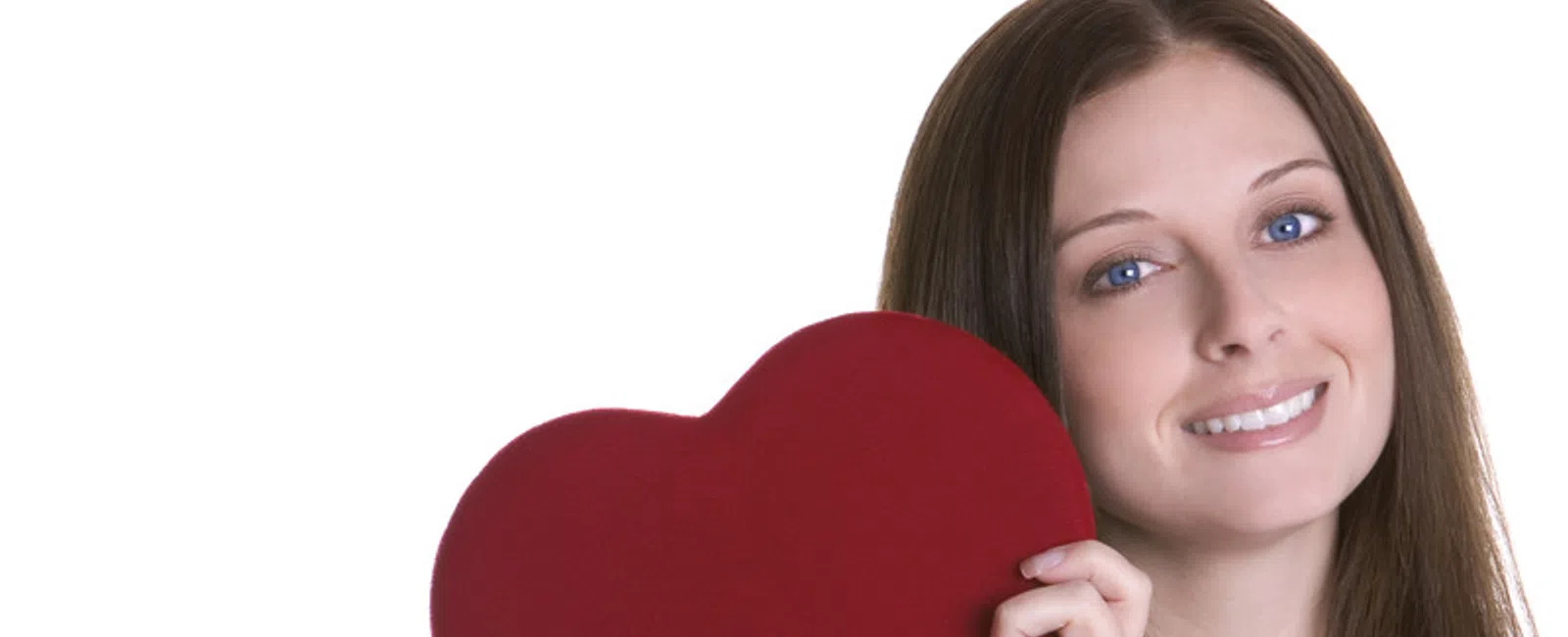 Smiling woman with blue eyes holding a large red heart shape against white background