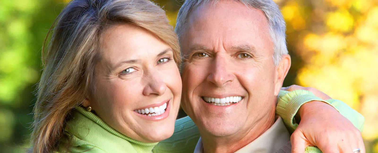 Smiling mature couple embracing outdoors with autumn foliage in the background