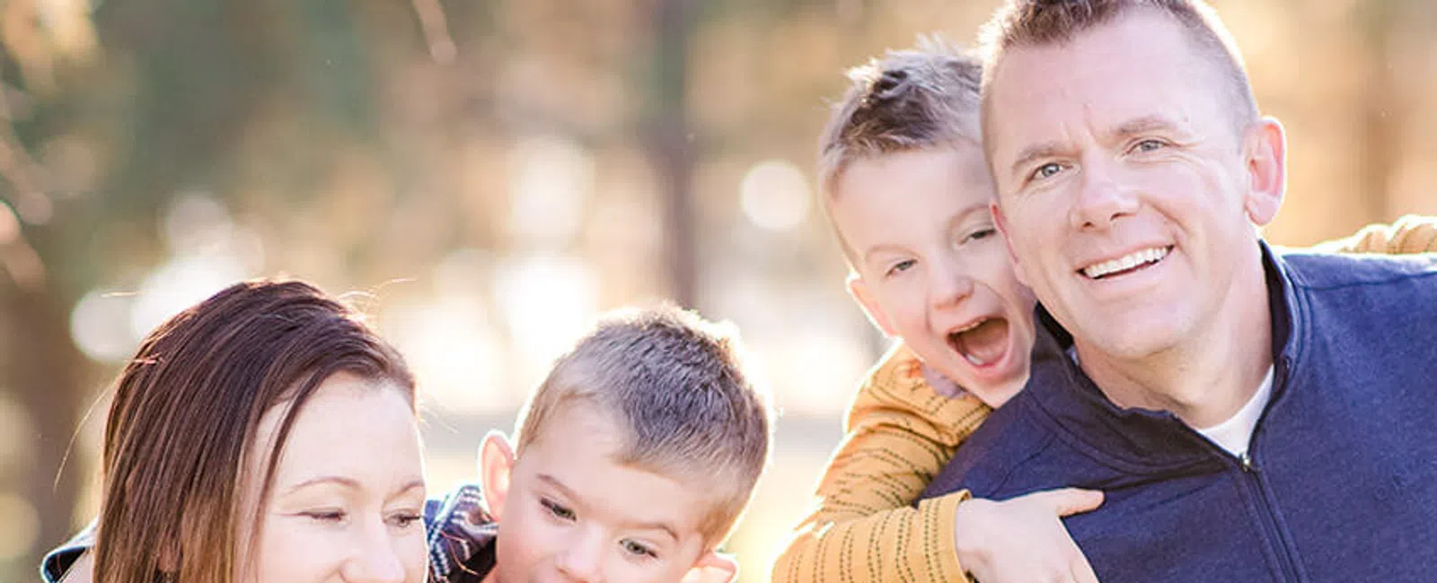 Happy family of five enjoying outdoor time together with parents and three children smiling and hugging.