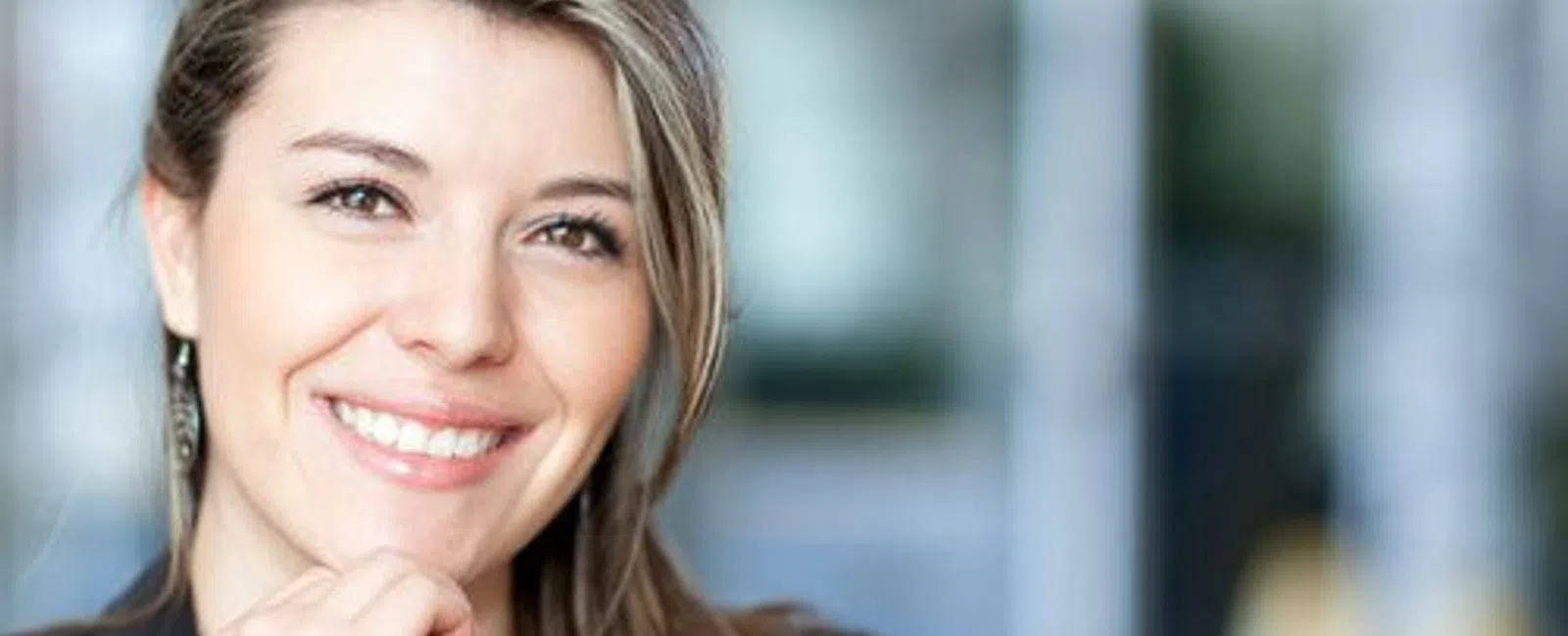 Smiling professional woman with long hair wearing business attire in a bright office environment