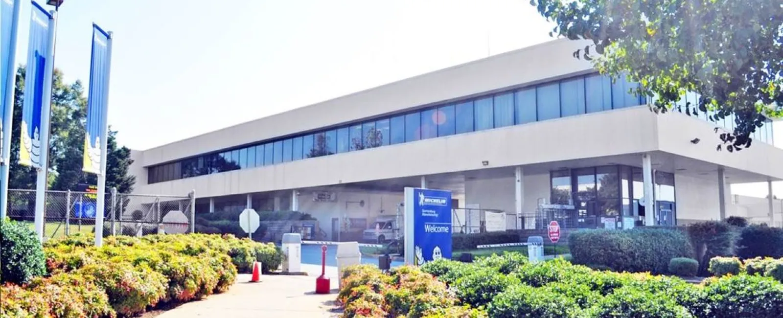 Modern office building with large windows surrounded by greenery and clear blue skies
