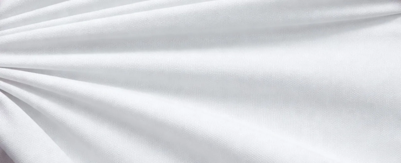 Soft white fabric with smooth folds and subtle texture arranged in a fan-like pattern
