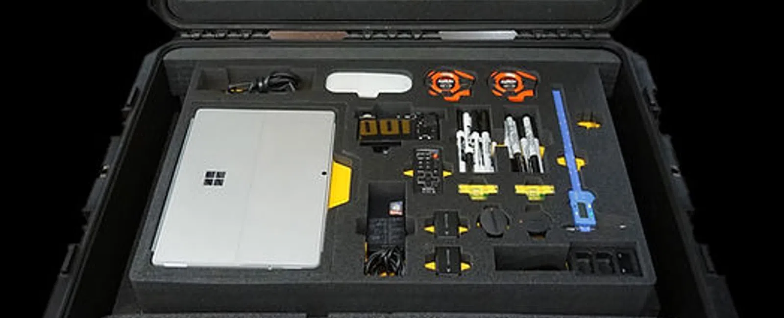 Open ToolKeepers Mobile Precision Kit case showing organized compartments and tools including a Microsoft Surface device.