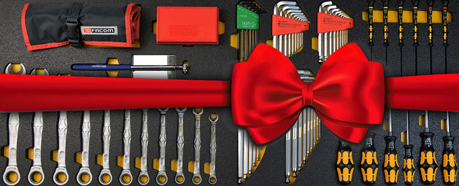 Set of organized wrenches, screwdrivers, and hex keys laid out neatly with a large red ribbon and bow.