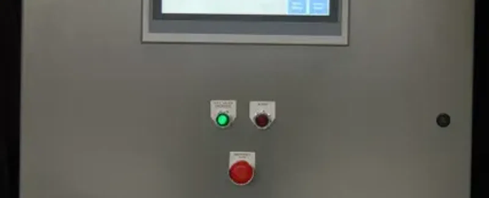 Industrial control panel with touchscreen display and three colored indicator buttons on gray metal surface