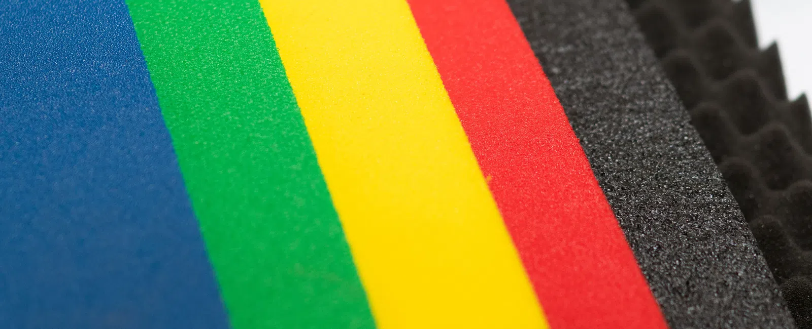 Close-up of colorful foam sheets in blue, green, yellow, red, and black foam with textured edges.