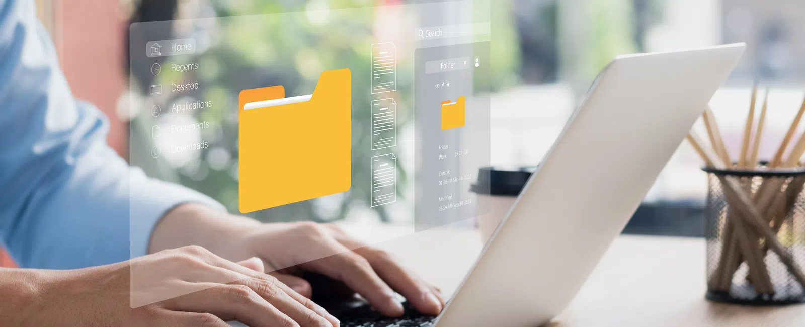 Person typing on laptop with digital folder icons and file interface graphics on screen.