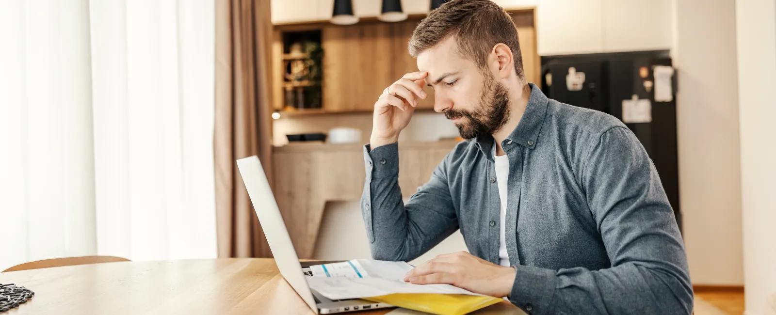 a man sitting at a table with a laptop and papers
