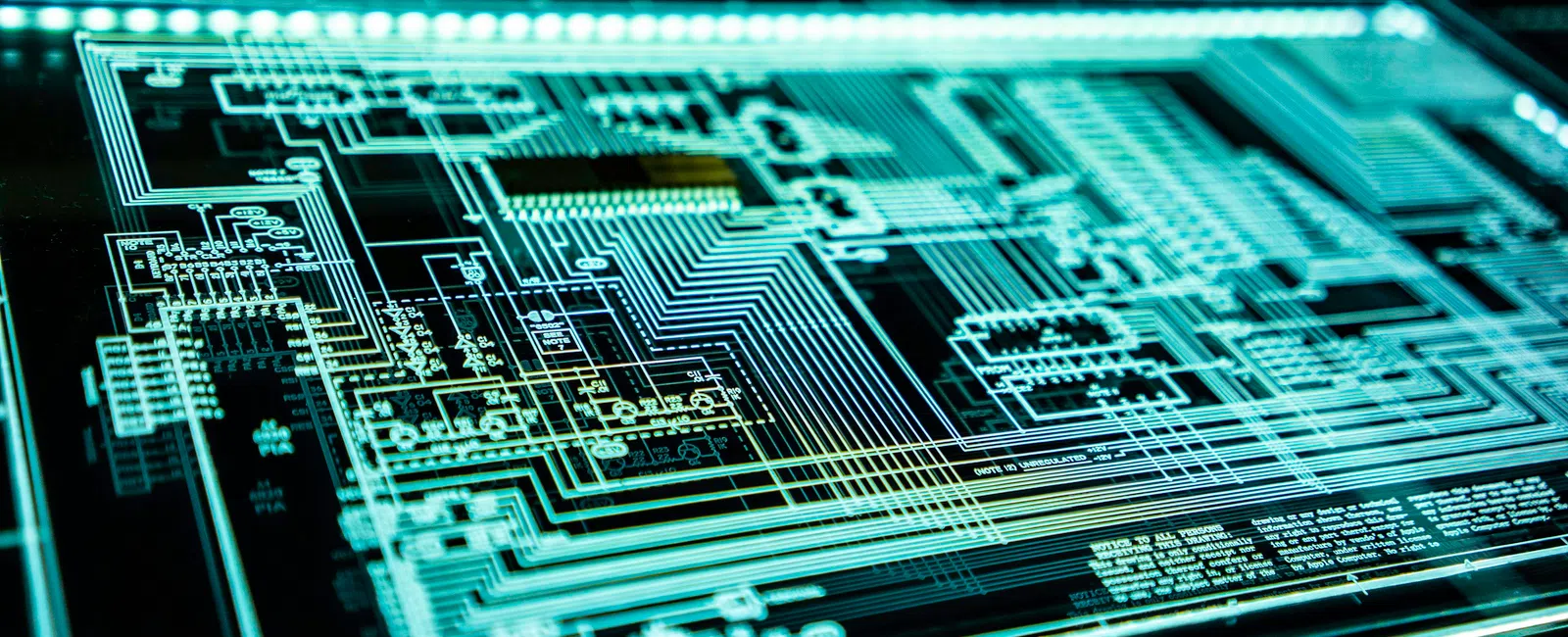 Close-up of illuminated electronic circuit board with intricate pathways and components on a dark background