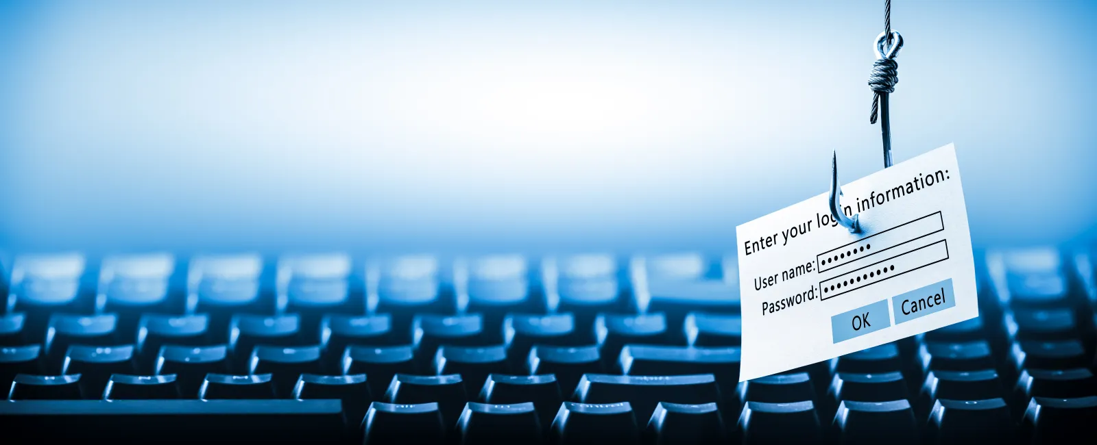 Fishing hook holding login form with username and password over computer keyboard representing phishing attack.