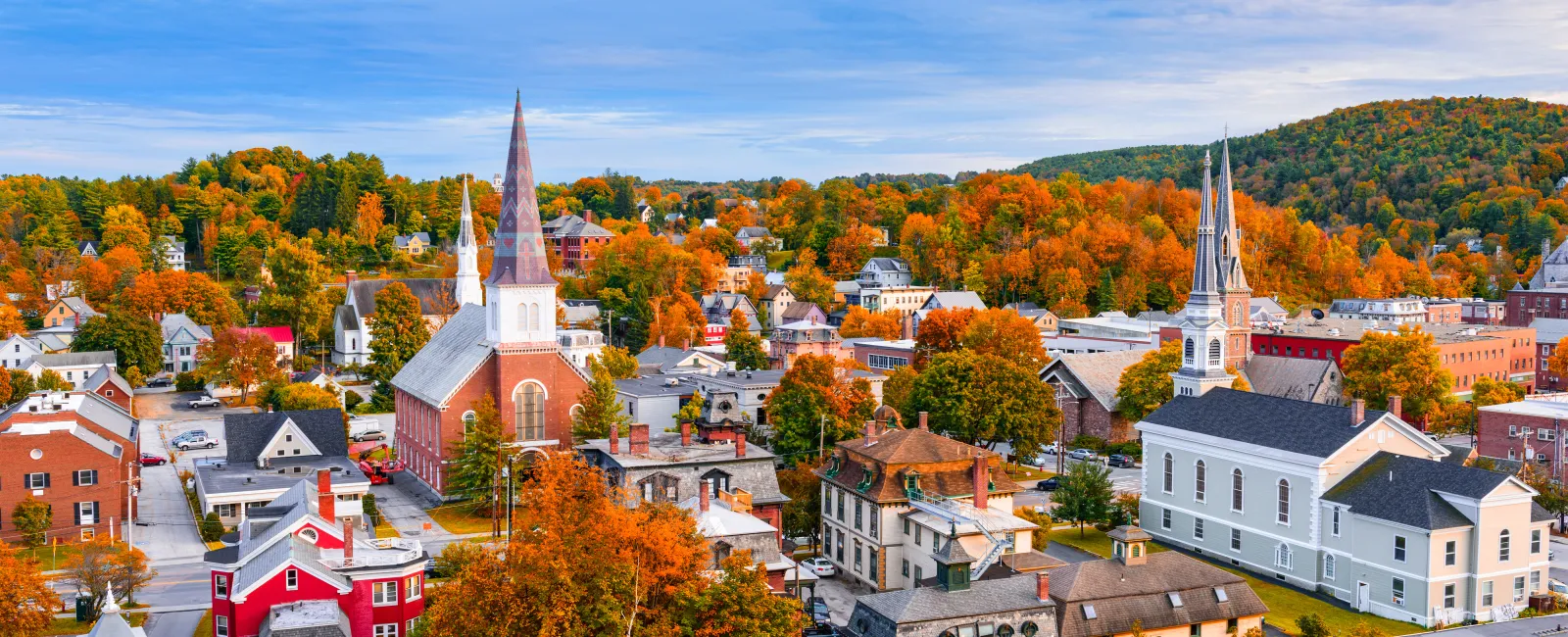 A vibrant small town in autumn with colorful trees, historic churches, and a clear blue sky above.