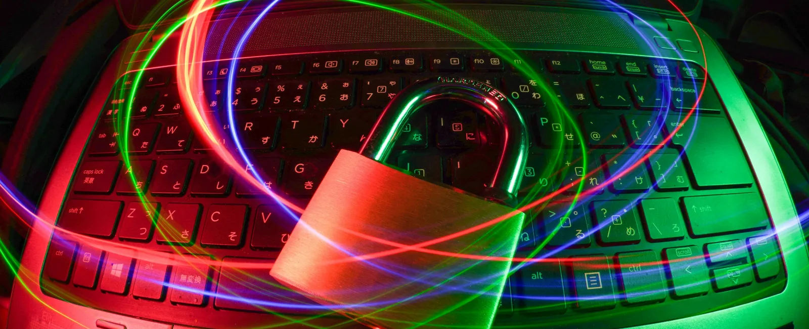 Padlock on laptop keyboard with swirling red, blue, and green light trails symbolizing cybersecurity protection.