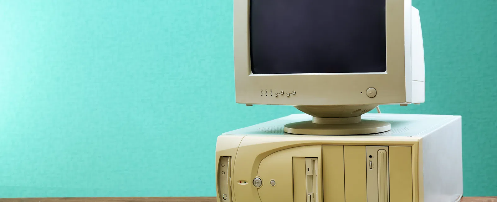 Retro beige desktop computer with CRT monitor, separate keyboard, and floppy disk drive on wooden table.