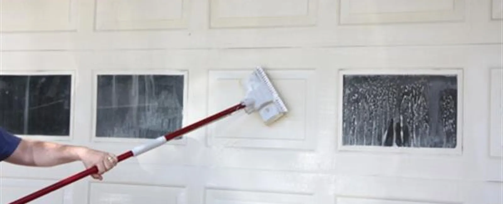 a hand holding a red and white object with a white wall and a window with a white frame