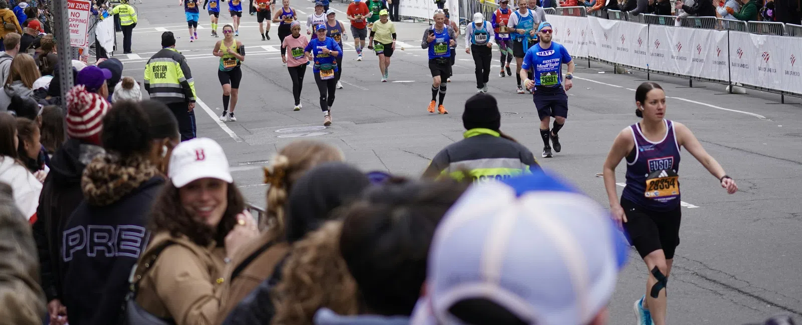 Runners participating in a marathon race on city streets with spectators and police presence.