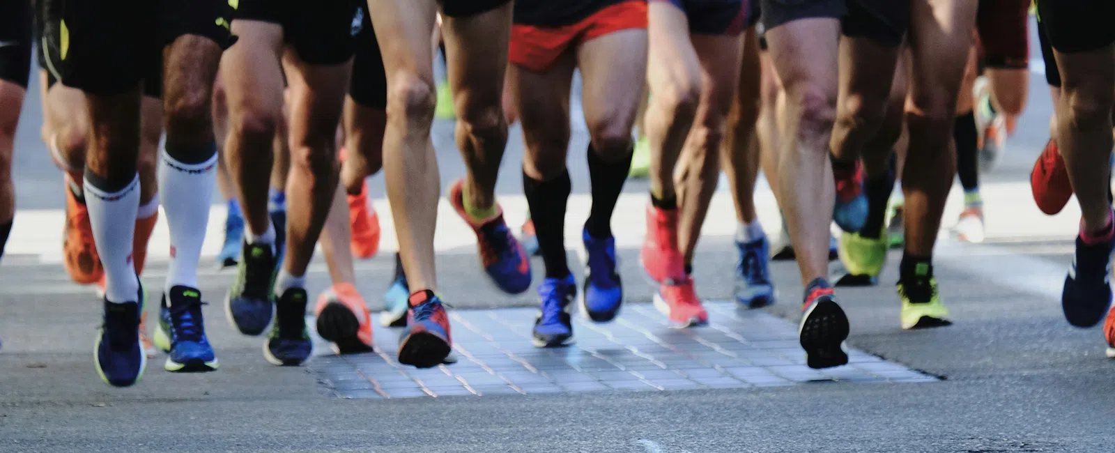 Close-up of marathon runners' legs and feet on a city street during a race event.