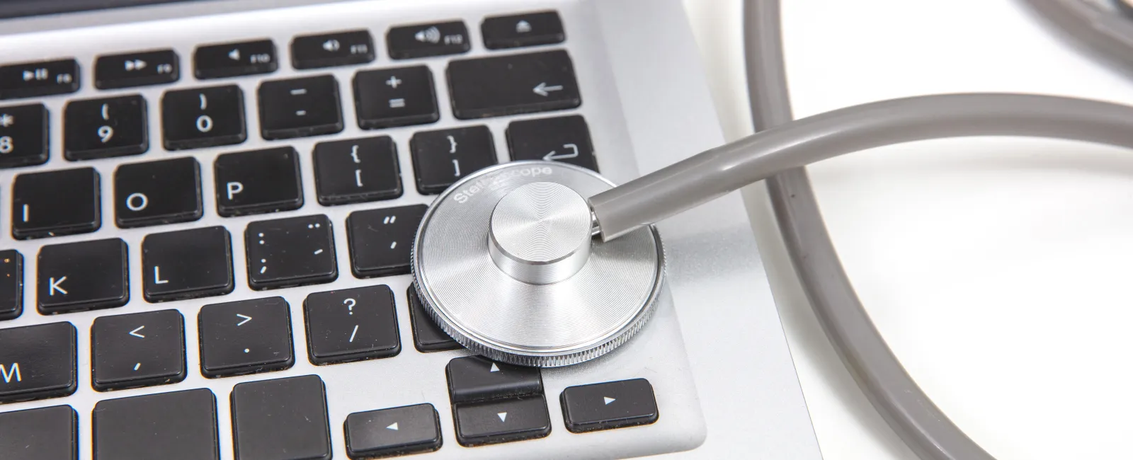 Silver stethoscope placed on a laptop keyboard symbolizing computer health check or IT diagnostics