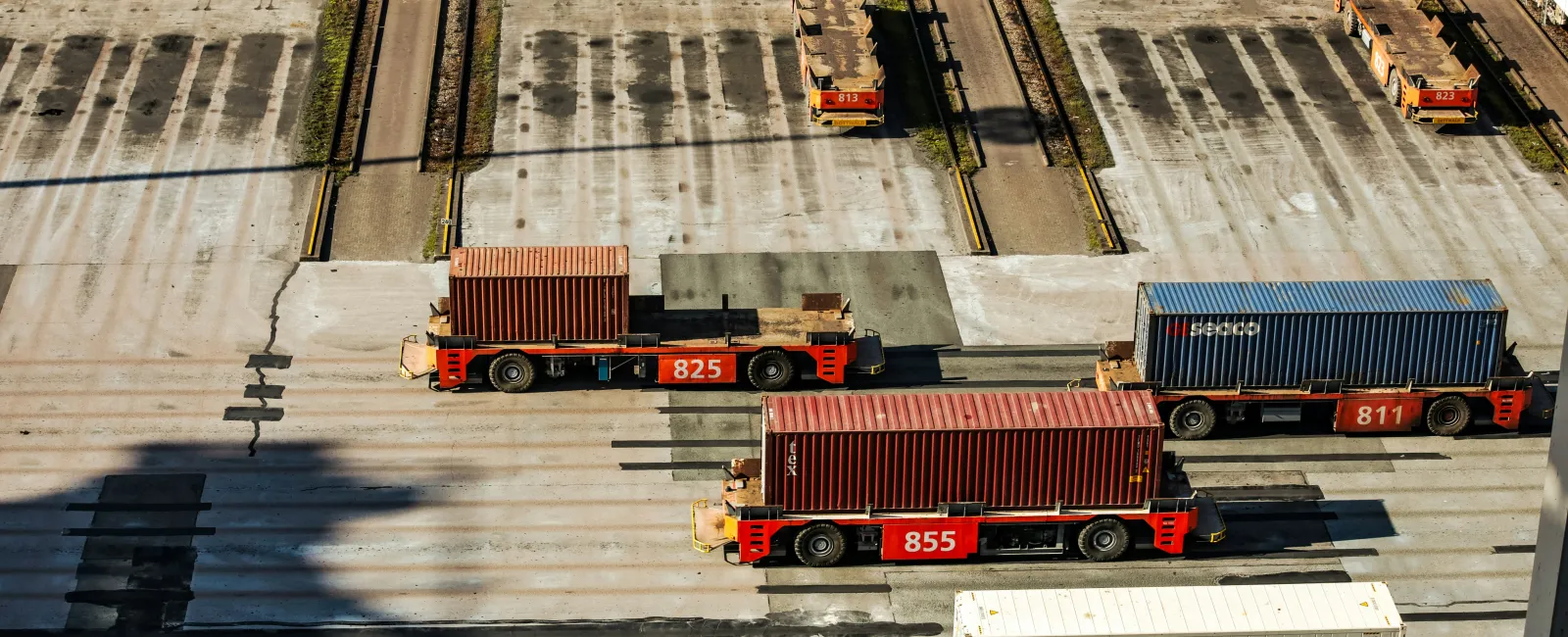 Autonomous container transport vehicles moving cargo containers at a shipping terminal emphasizing the importance of cyber security in supply chain logistics.