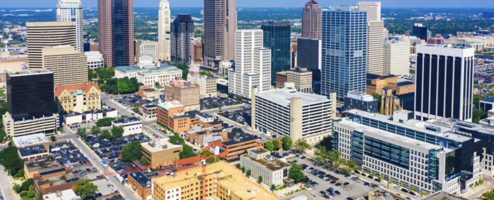 Aerial view of a modern city skyline with high-rise buildings under a clear blue sky on a sunny day