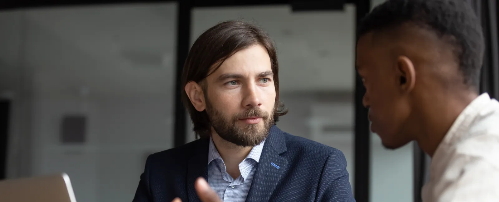 Two men having a focused business discussion in an office with a laptop and documents on the table.