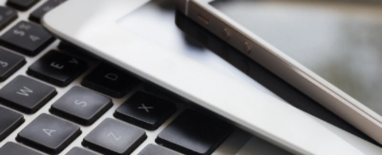 Smartphone and tablet placed on a laptop keyboard, representing modern digital technology and connectivity.