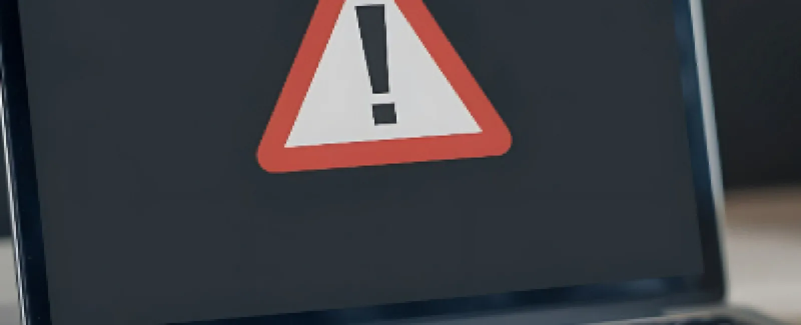 Laptop displaying a warning alert with a red triangle and exclamation mark on the screen.