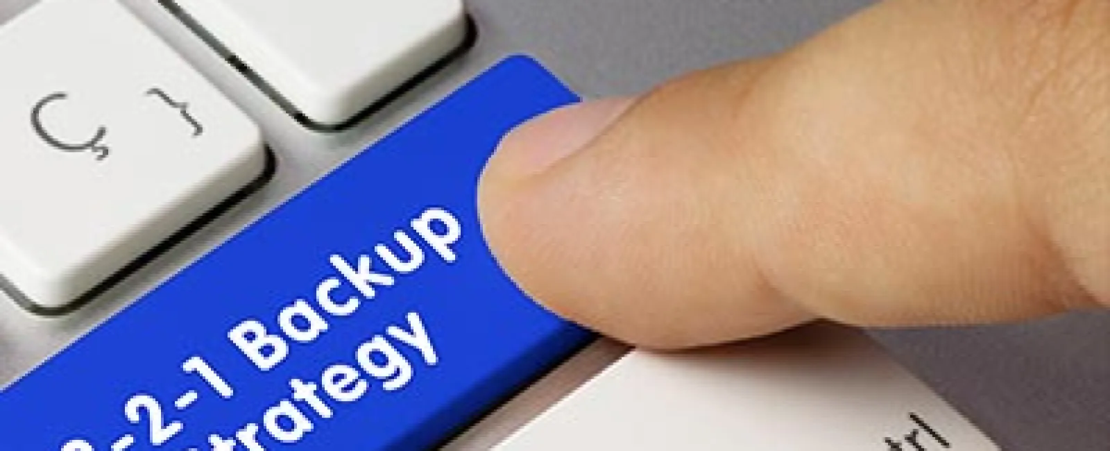Finger pressing a blue keyboard key labeled 3-2-1 Backup Strategy on a white computer keyboard.
