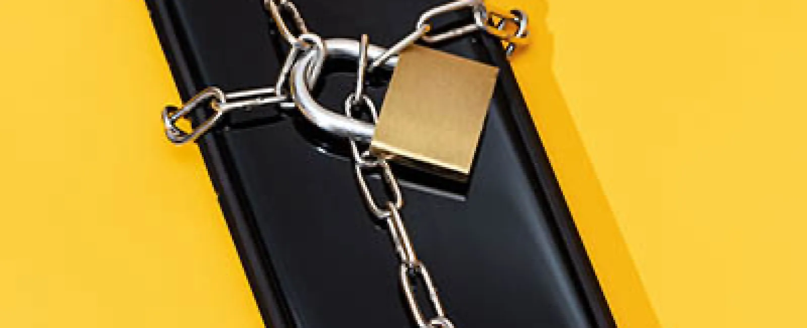 Black smartphone secured with silver chain and gold padlock on yellow background symbolizing data security.