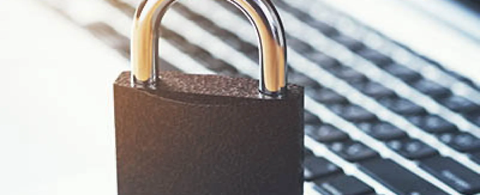Black padlock on a silver laptop keyboard symbolizing cybersecurity and data protection.