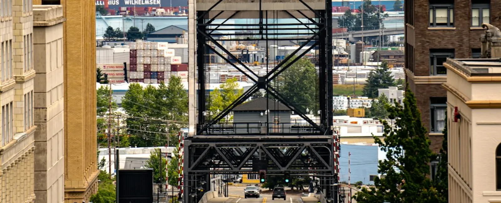 Downtown Tacoma street leading to the Port of Tacoma lift bridge with traffic lights and buildings on either side.