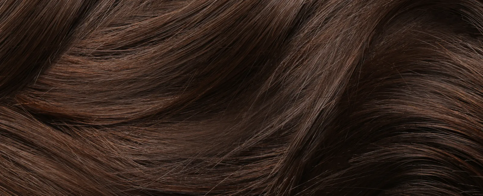 Close-up of smooth, shiny brown hair strands with natural highlights and soft waves in a flowing pattern.
