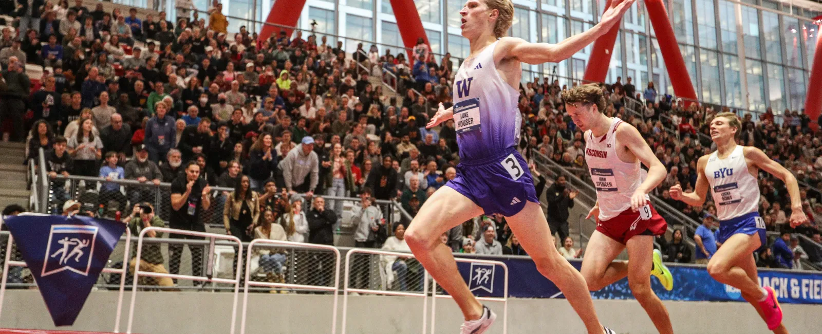 a group of people running on a track with a crowd watching