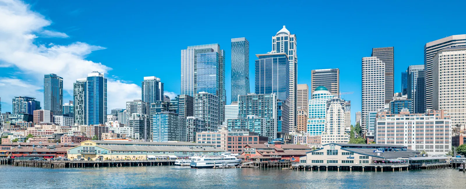 Seattle city skyline with tall skyscrapers and waterfront under a clear blue sky.