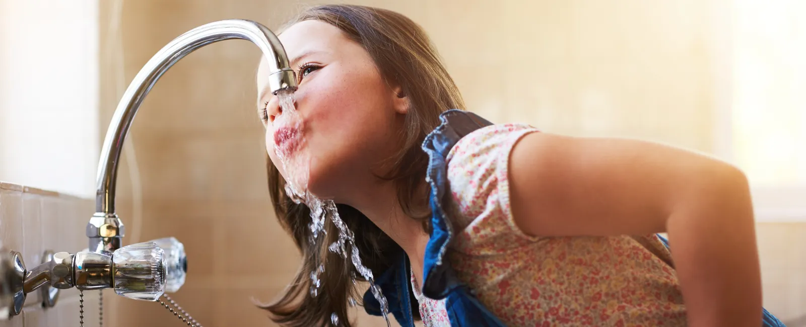 child drinking water from faucet