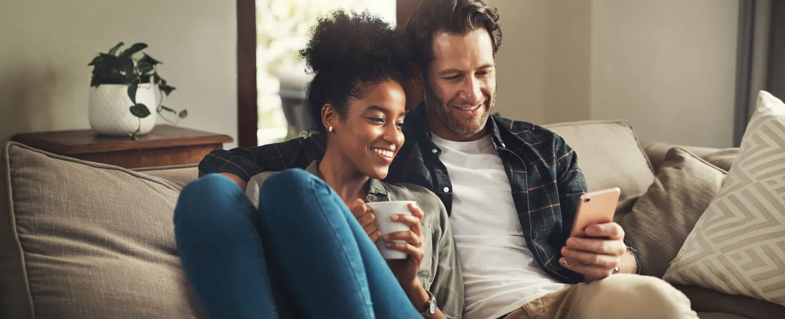 a man and a woman sitting on a couch and looking at a phone