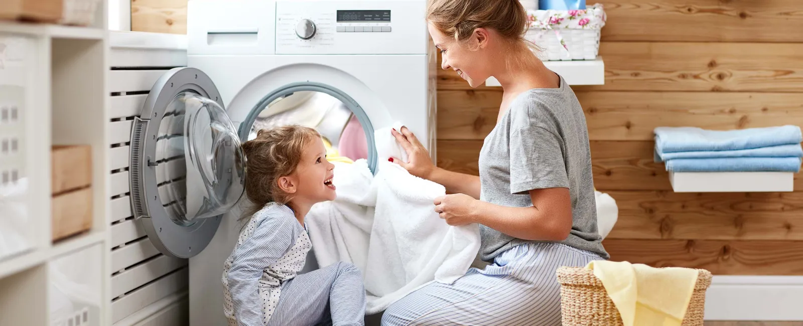 a person and a child sitting on the floor next to a washing machine