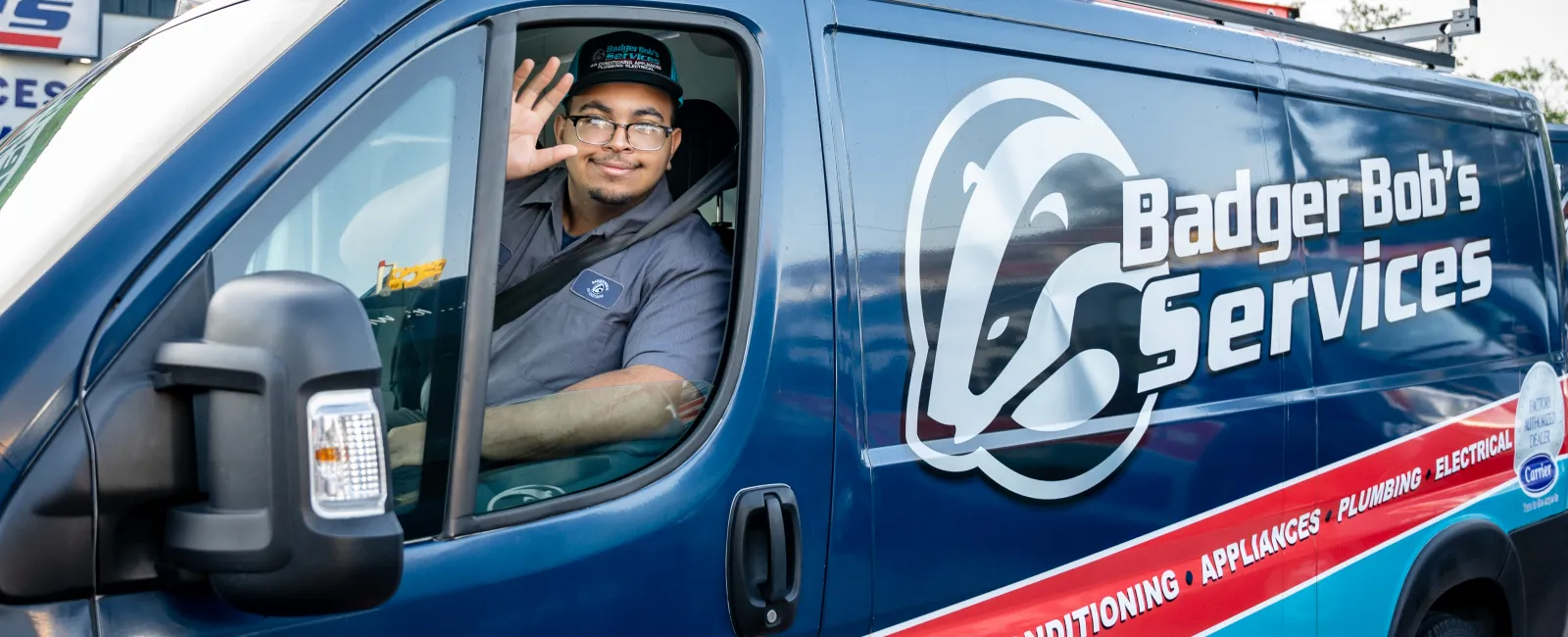 Technician in uniform waving from the driver seat of a Badger Bob's Services van with company branding.