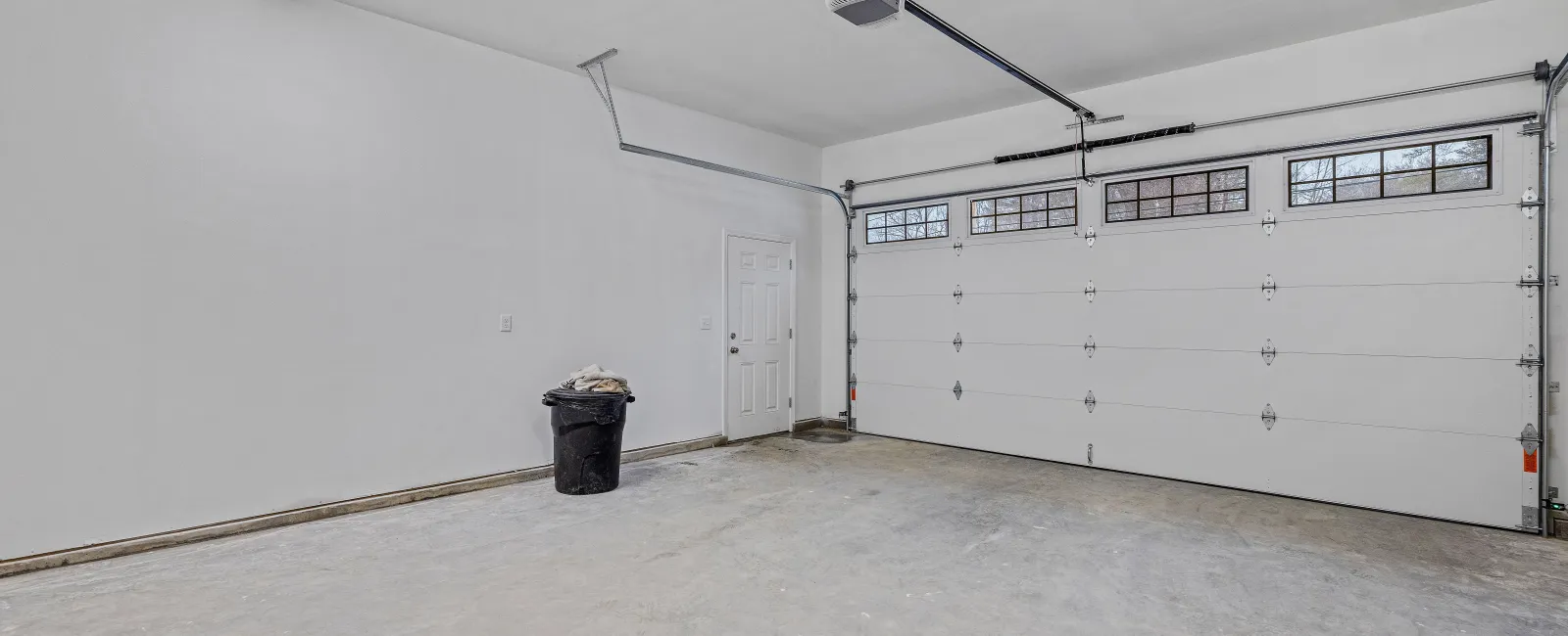 a room with a trash can and a white wall