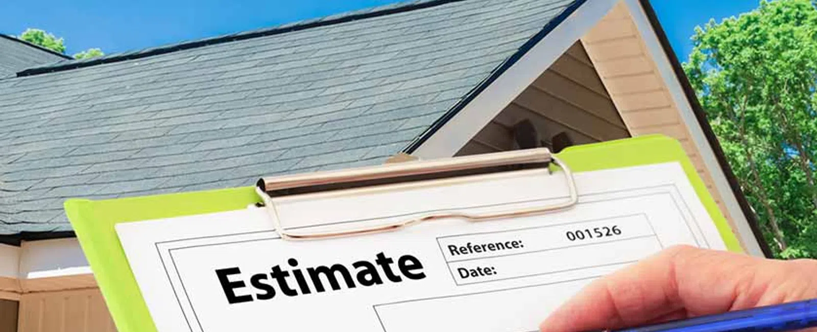 Hand holding pen filling out a roofing estimate form with house and blue sky in the background.